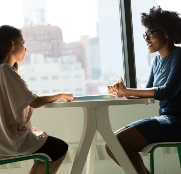 two women sitting at a table talking