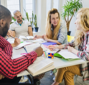 Teachers collaborating at a table during a professional development workshop with notebooks and materials