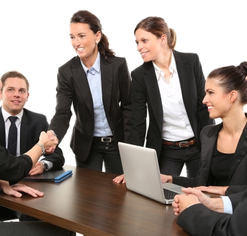 men and women around a conference table shaking hands