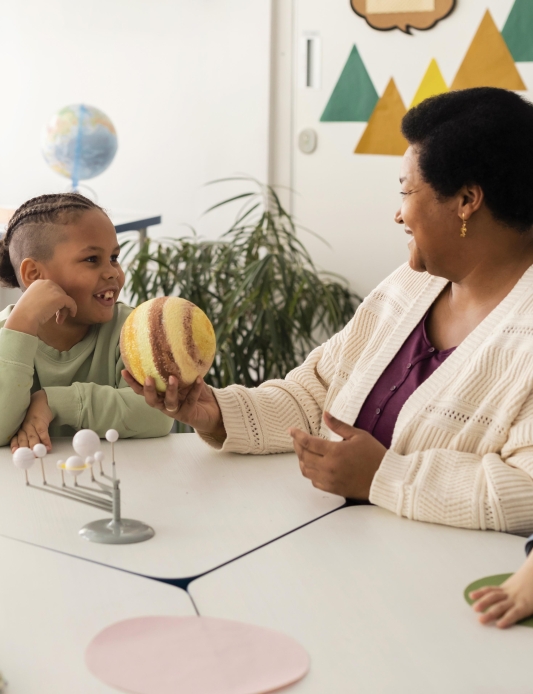 Teacher showing a model planet to students during a classroom science activity